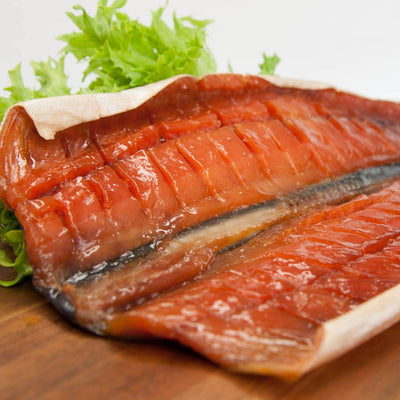 Wildlachs gedörrt – Filet aufgeschnitten auf Holzbrett mit Salat