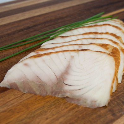 Störfilet in Scheiben geräuchert – Filetscheiben auf Holzbrett mit Schnittlauch