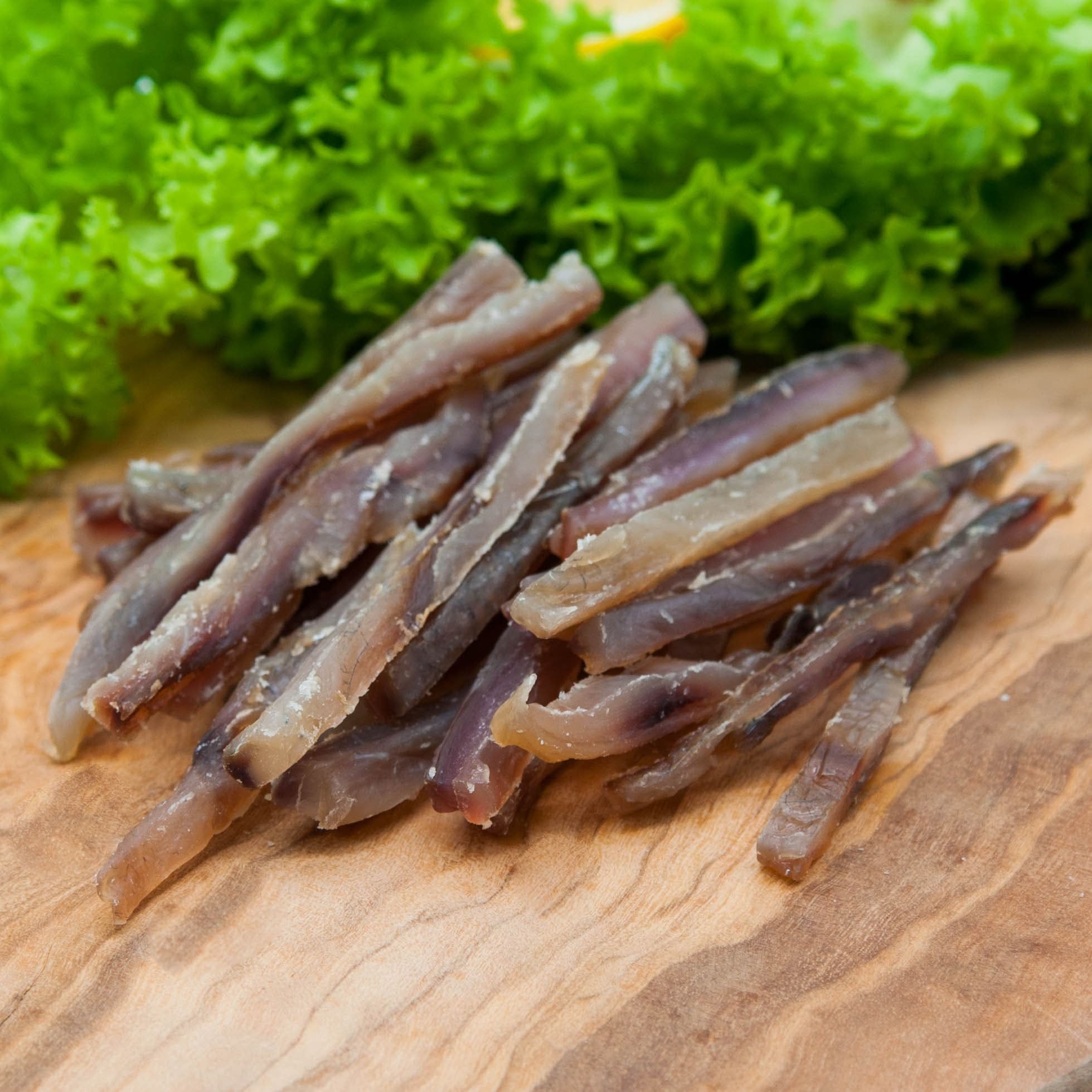 Filetstreifen vom Silberkarpfen gedörrt – aufgehäufte Streifen mit Salat