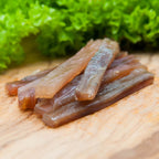 Filetstreifen vom Wels gedörrt – Stapel auf Holzbrett mit Salat