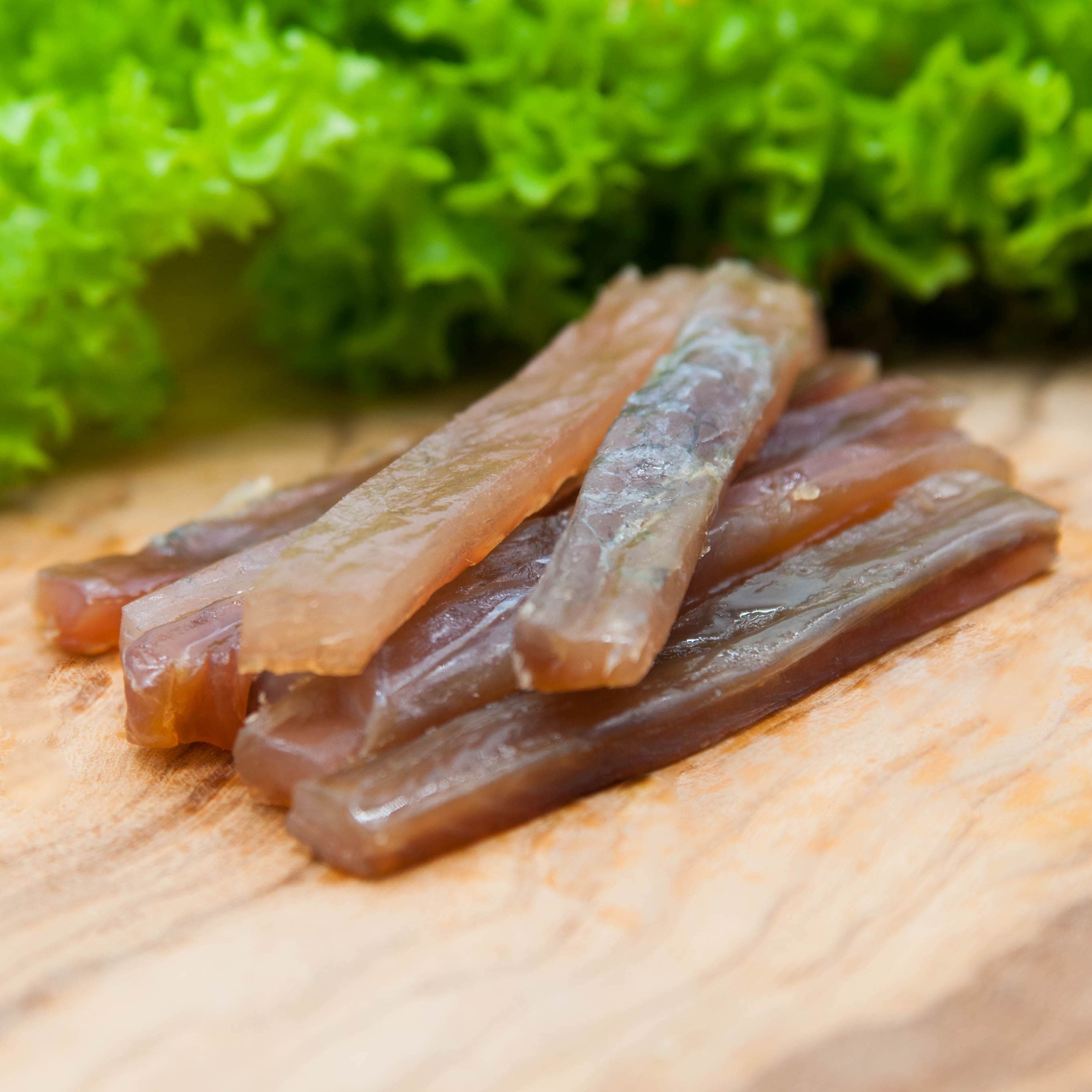 Filetstreifen vom Wels gedörrt – Stapel auf Holzbrett mit Salat